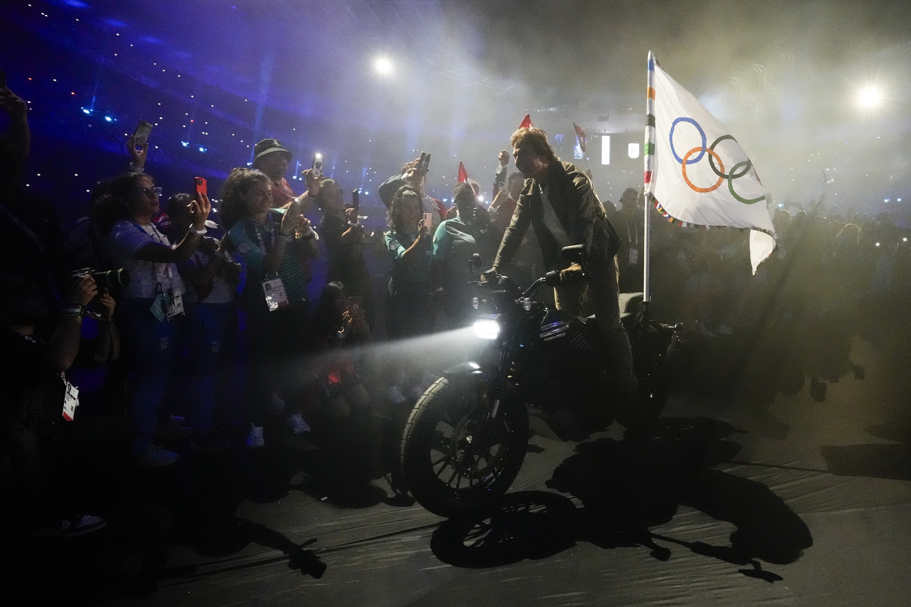 Tom Cruise monta en una motocicleta con la bandera olímpica durante la ceremonia de clausura.