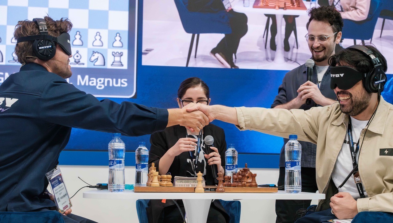 Carlsen saluda a Nakamura, con Rozman de presentador.