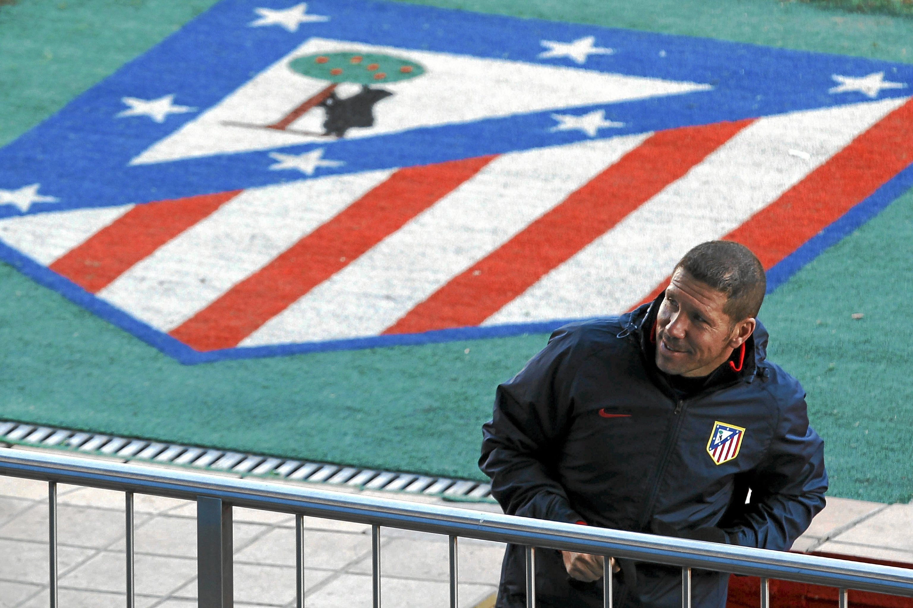 Simeone con el escudo del Atlético de fondo.