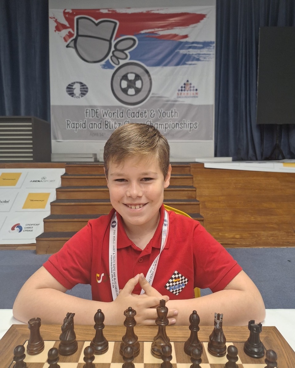 El joven posa frente a un tablero.