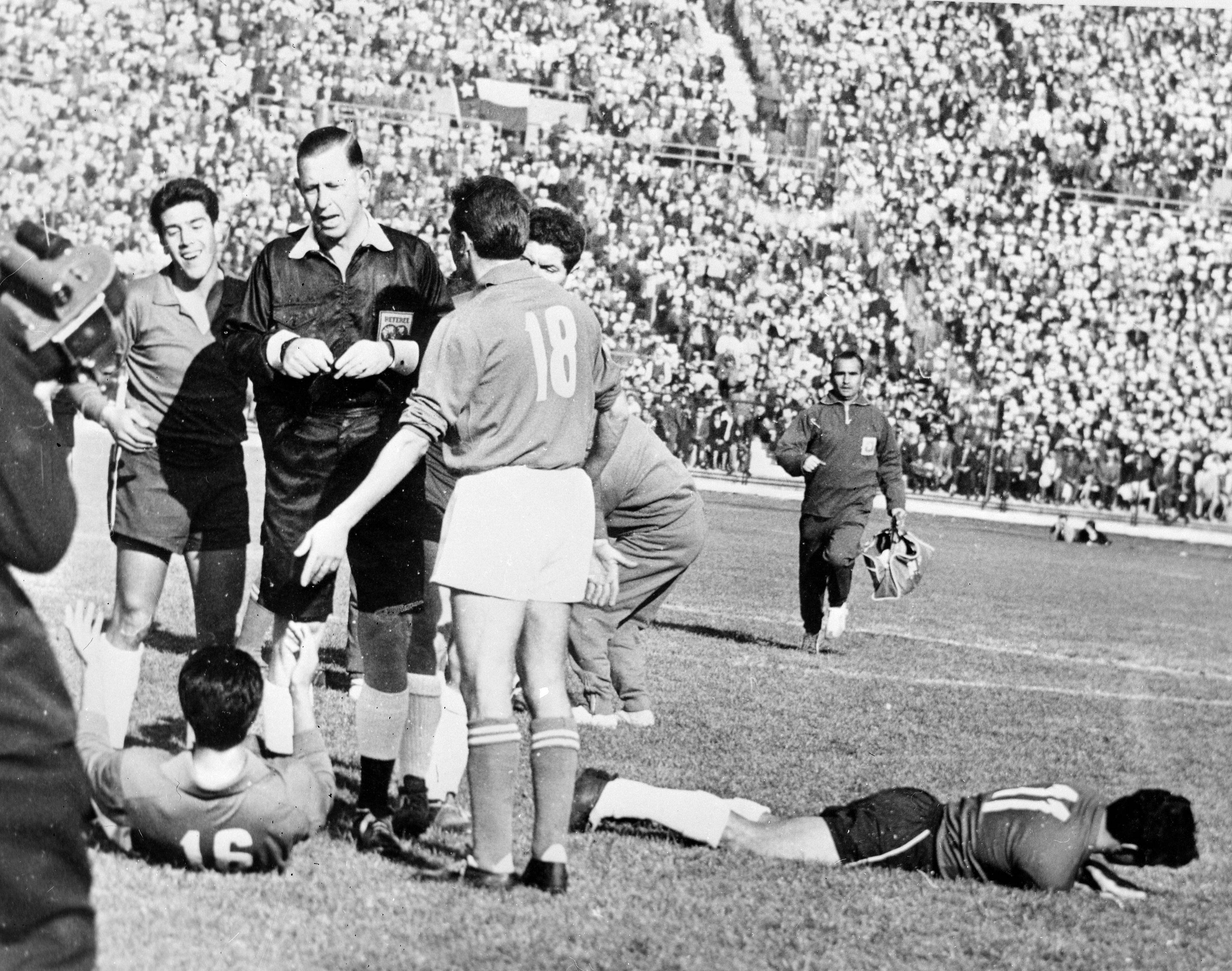 El árbitro inglés Aston expulsa a un jugador italiano, con el chileno en el suelo tras una entrada.